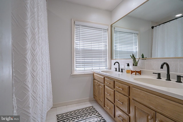 bathroom with a sink, tile patterned floors, backsplash, and double vanity