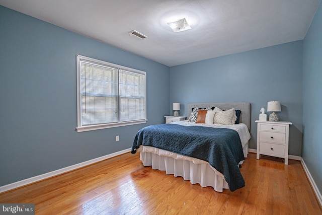 bedroom featuring baseboards, wood finished floors, and visible vents