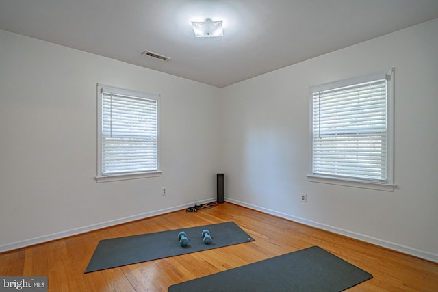 exercise room featuring baseboards, a wealth of natural light, wood finished floors, and visible vents