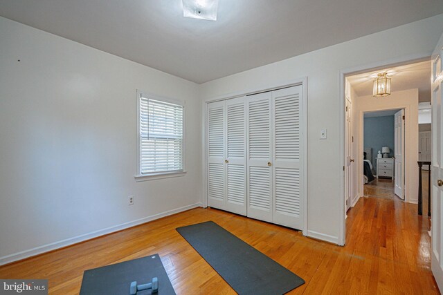 workout room with baseboards and light wood-type flooring