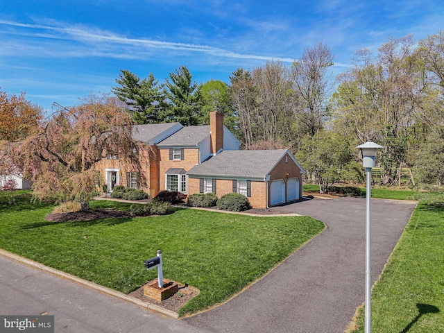 view of front facade with a garage, a front lawn, a chimney, brick siding, and driveway