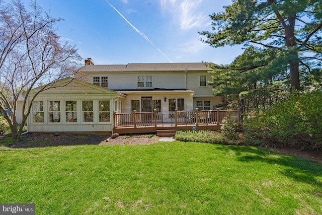 rear view of house featuring a lawn, a chimney, and a deck