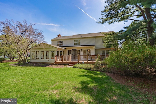 back of property featuring a yard, a deck, a chimney, and a sunroom