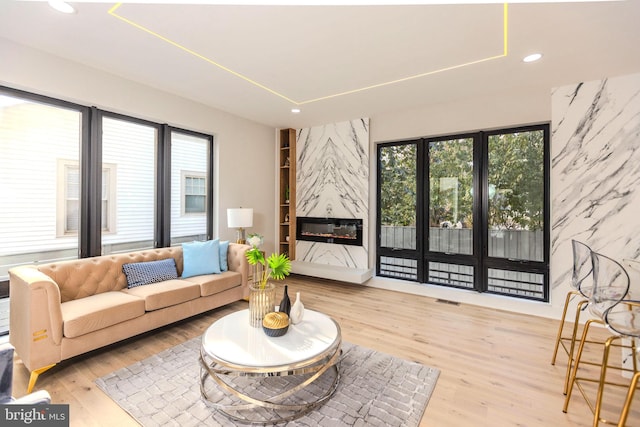 living room featuring recessed lighting, a high end fireplace, wood finished floors, and visible vents