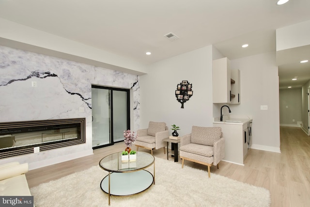 living room featuring a premium fireplace, recessed lighting, baseboards, and light wood-style flooring