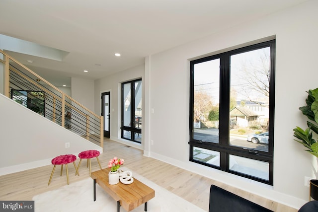 living area with recessed lighting, baseboards, wood finished floors, and stairway