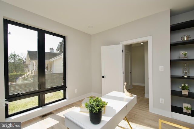 interior space featuring baseboards, visible vents, plenty of natural light, and light wood-type flooring