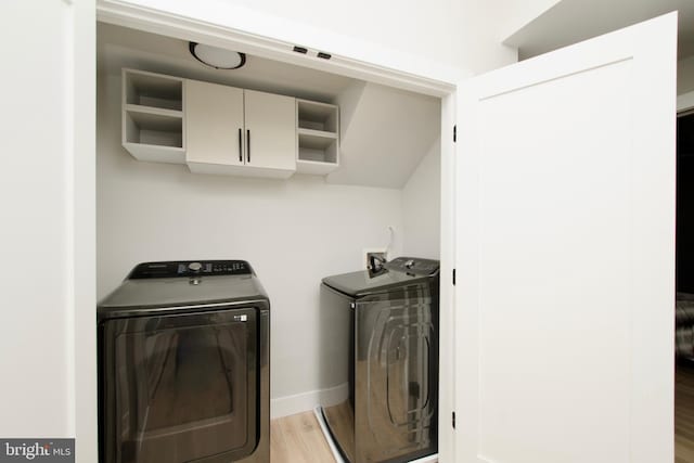 laundry area featuring baseboards, laundry area, wood finished floors, and washer and clothes dryer