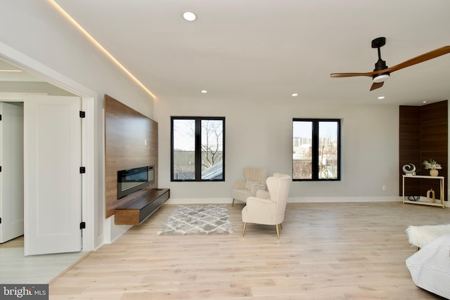 living area with recessed lighting, a ceiling fan, a wealth of natural light, and light wood-style flooring