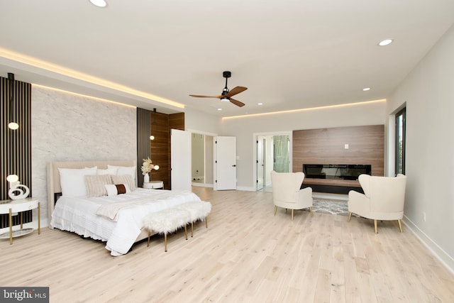 bedroom featuring recessed lighting, baseboards, a glass covered fireplace, and wood finished floors