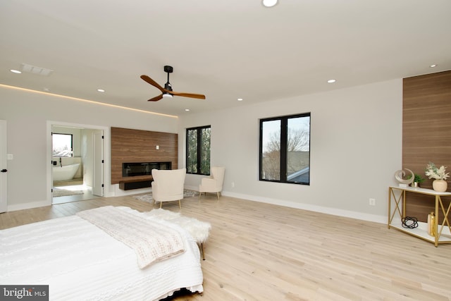 bedroom with recessed lighting, baseboards, a fireplace, and light wood finished floors