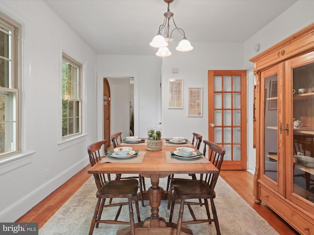 dining room with wood finished floors, a chandelier, baseboards, and french doors