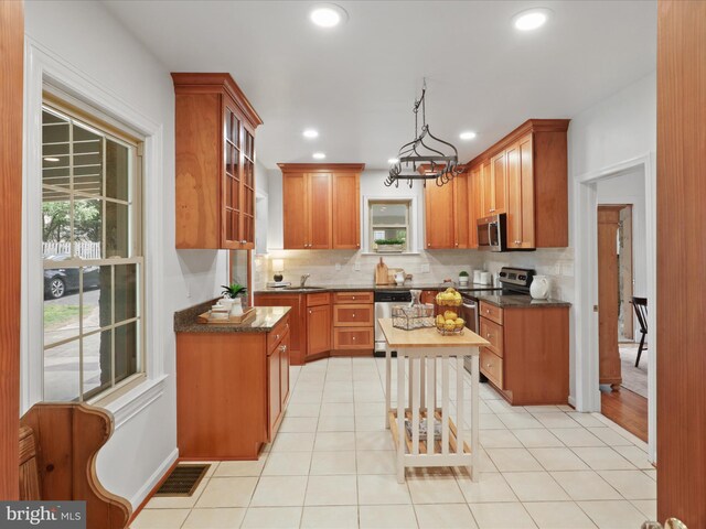 kitchen with appliances with stainless steel finishes, decorative backsplash, plenty of natural light, recessed lighting, and brown cabinetry