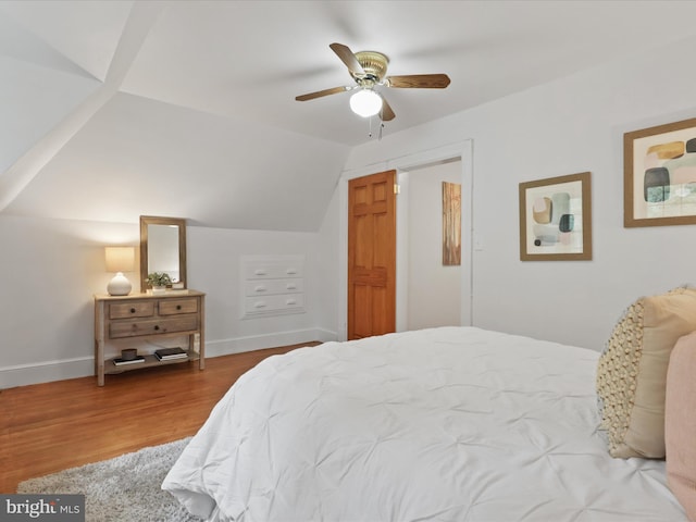bedroom featuring lofted ceiling, wood finished floors, baseboards, and ceiling fan