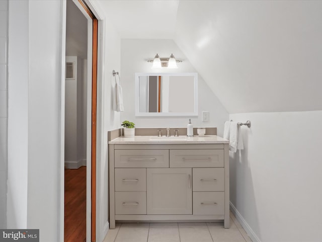 bathroom with vaulted ceiling, vanity, baseboards, and tile patterned flooring