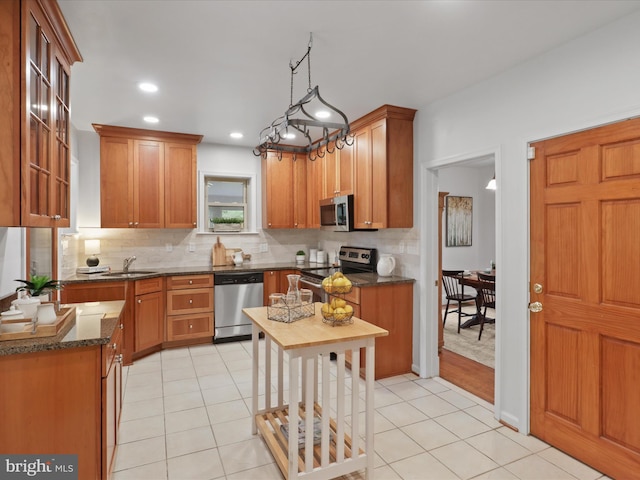 kitchen with stainless steel appliances, backsplash, light tile patterned floors, brown cabinetry, and recessed lighting