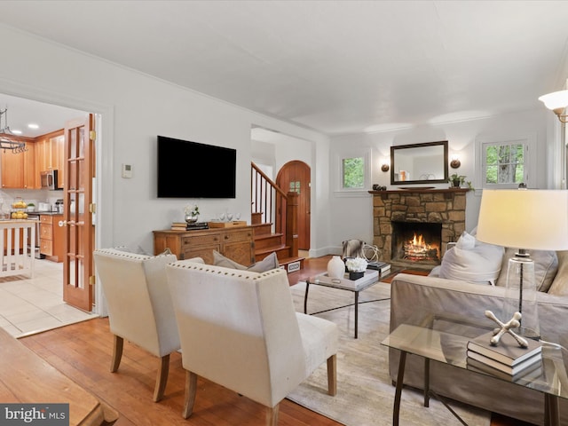 living room featuring light wood-style floors, a fireplace, arched walkways, and a chandelier