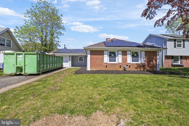 view of front facade with brick siding, a front lawn, and roof mounted solar panels