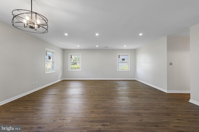 empty room featuring recessed lighting, baseboards, an inviting chandelier, and dark wood finished floors