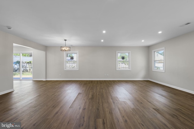 unfurnished dining area featuring visible vents, baseboards, dark wood-style floors, a notable chandelier, and recessed lighting