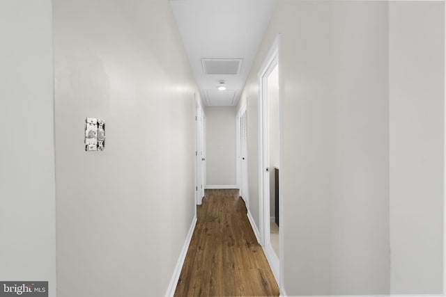 hallway featuring baseboards, attic access, wood finished floors, and visible vents