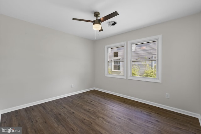spare room featuring baseboards, ceiling fan, and dark wood finished floors