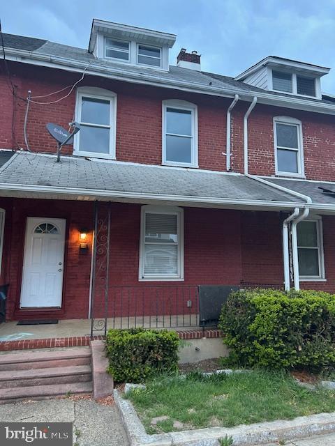 multi unit property with a porch and brick siding