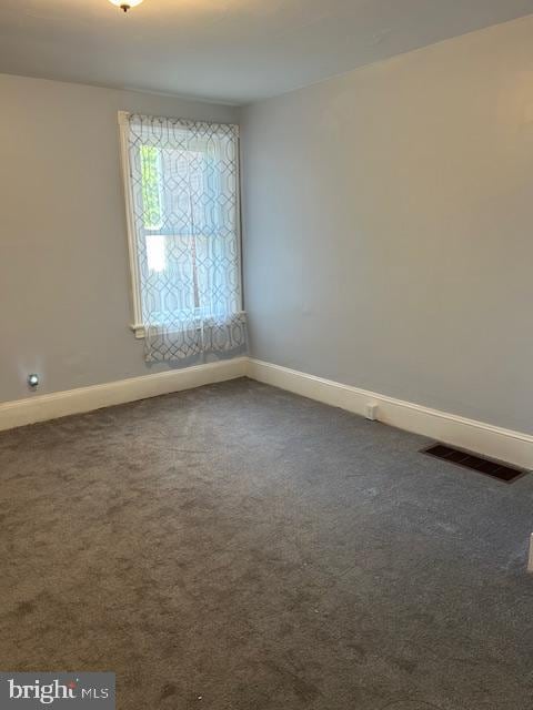 carpeted spare room featuring baseboards and visible vents