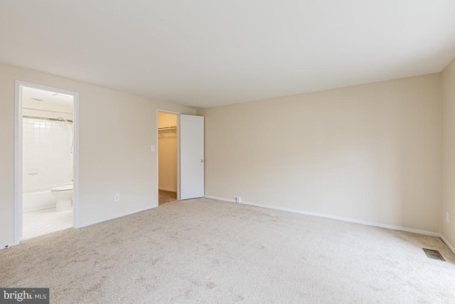 unfurnished bedroom with baseboards, visible vents, carpet floors, and a walk in closet