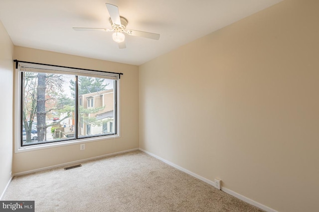 unfurnished room featuring light carpet, baseboards, a ceiling fan, and visible vents