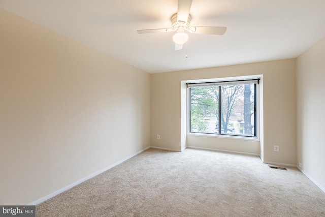 spare room featuring baseboards, a ceiling fan, visible vents, and carpet
