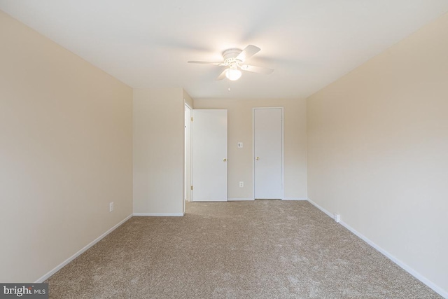 carpeted empty room featuring a ceiling fan and baseboards