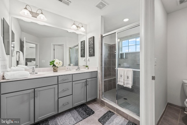 bathroom featuring tile patterned flooring, double vanity, toilet, visible vents, and a stall shower