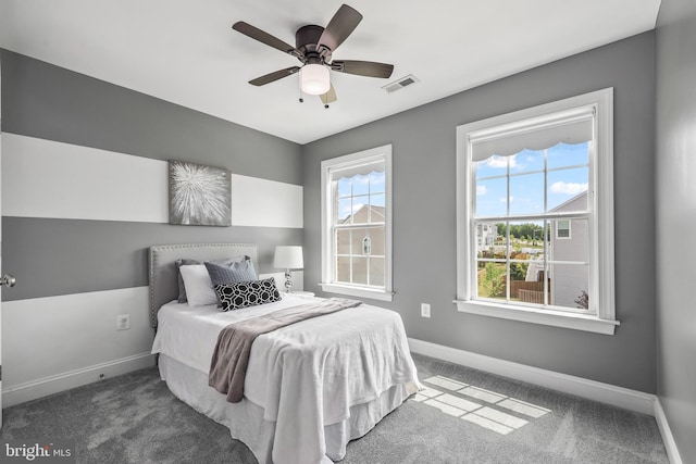 carpeted bedroom with baseboards, a ceiling fan, and visible vents