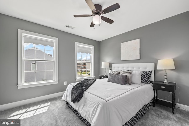 carpeted bedroom featuring baseboards, a ceiling fan, and visible vents