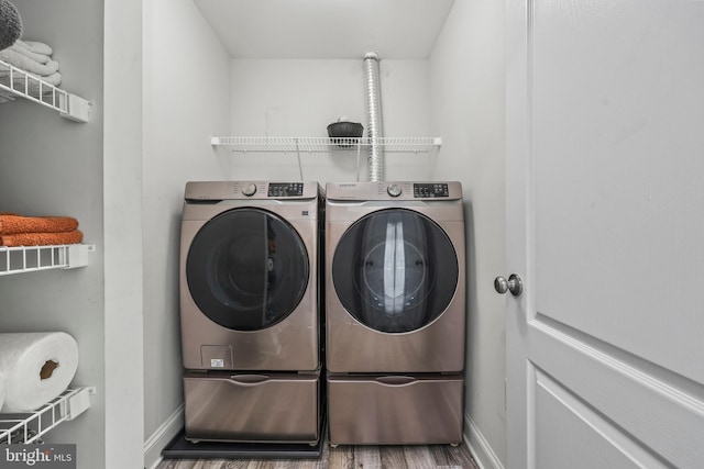 laundry area with laundry area, baseboards, wood finished floors, and washing machine and clothes dryer
