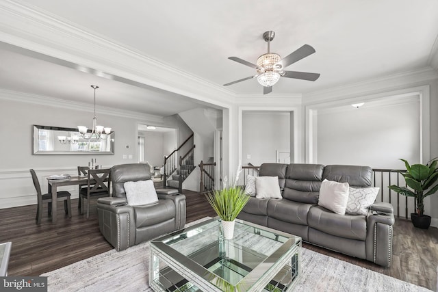 living area featuring stairway, ornamental molding, wood finished floors, and ceiling fan with notable chandelier