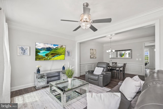 living room with crown molding, wood finished floors, ceiling fan with notable chandelier, and a wainscoted wall