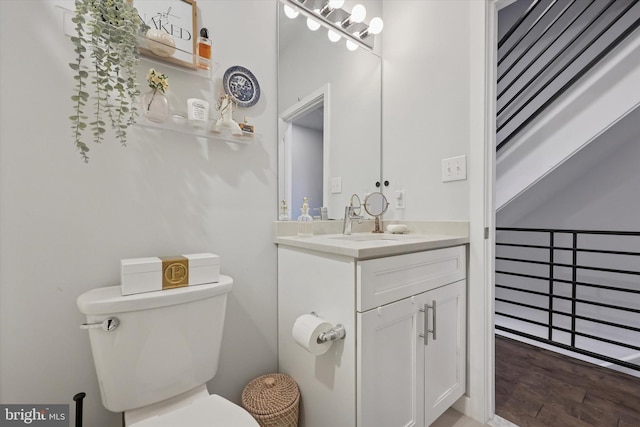 half bathroom with vanity, toilet, and wood finished floors
