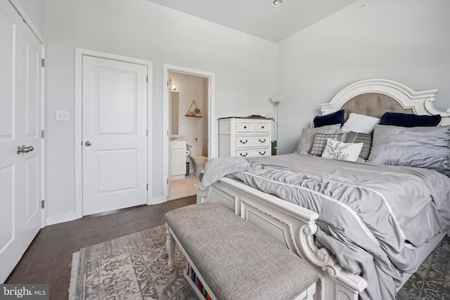 bedroom featuring baseboards, ensuite bath, and wood finished floors