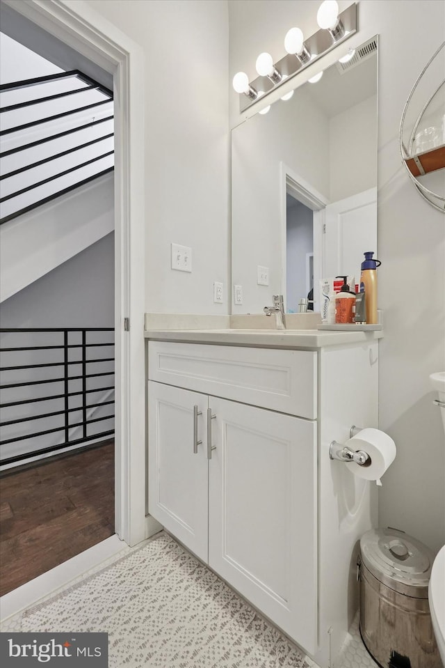 half bath with toilet, visible vents, and vanity