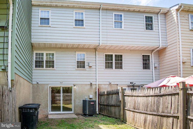 rear view of property with central air condition unit and fence