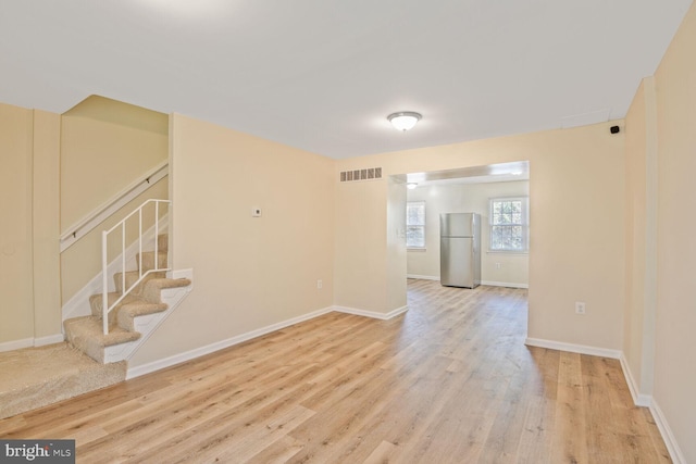 spare room featuring baseboards, visible vents, wood finished floors, and stairway