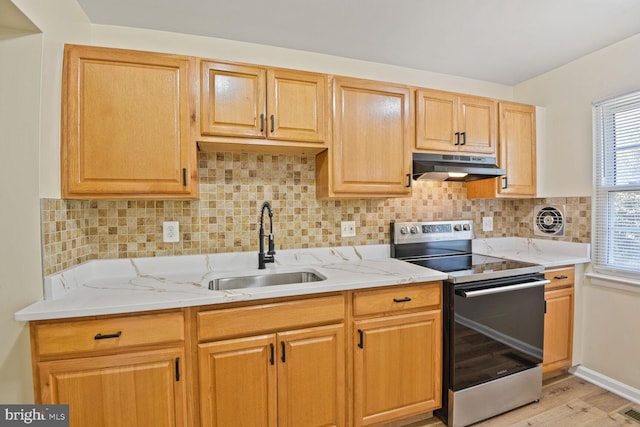 kitchen featuring a sink, light wood-style floors, electric stove, backsplash, and under cabinet range hood