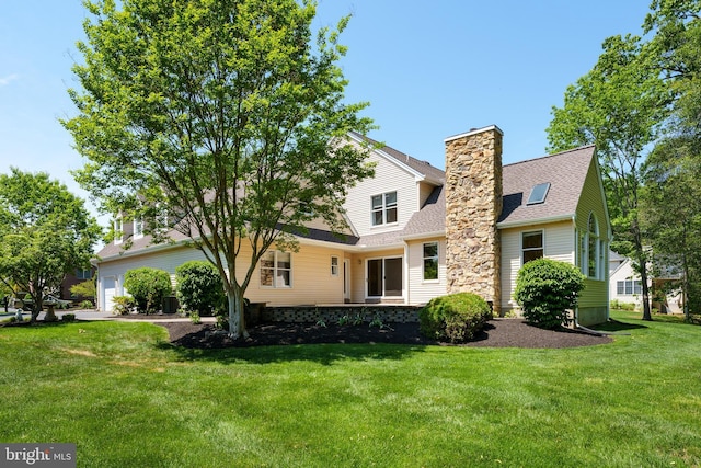 back of property featuring a yard, a chimney, a garage, and a shingled roof