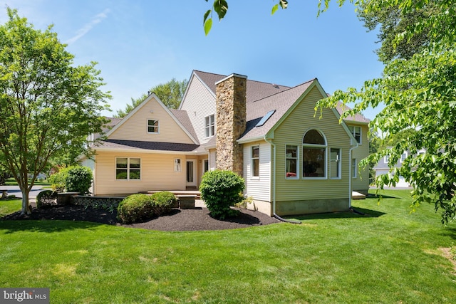 rear view of house featuring a yard, a chimney, and a shingled roof