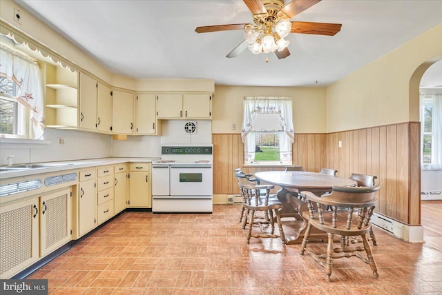 kitchen with arched walkways, cream cabinets, wainscoting, and double oven range