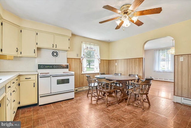 kitchen featuring range with two ovens, arched walkways, wainscoting, and cream cabinetry