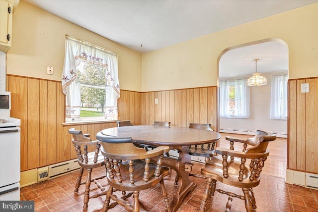 dining room featuring a healthy amount of sunlight, a wainscoted wall, and arched walkways