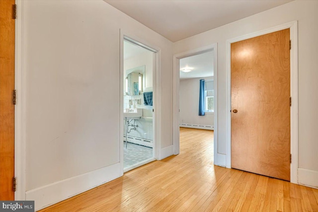 interior space with baseboards, baseboard heating, and light wood-type flooring
